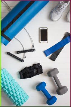 an assortment of exercise equipment including dumbs, phone and water bottle on a white surface