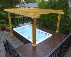 a hot tub sitting on top of a wooden deck under a pergolated roof