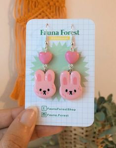 a pair of pink earrings with bunny ears and hearts hanging from it's ear wires