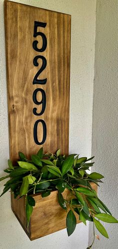 a wooden sign with numbers on it and a potted plant in the bottom right corner