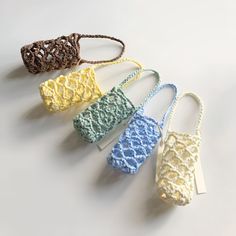 four crocheted purses are lined up on a white surface with tags attached to them