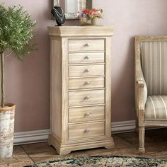 a white dresser sitting next to a chair and a potted plant in a room