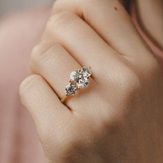 a woman's hand holding a three stone ring