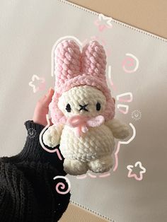 a crocheted stuffed animal is being held up by someone's hand in front of a pink and white background