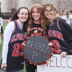 two girls are holding a sign and posing for the camera with another girl in front of them