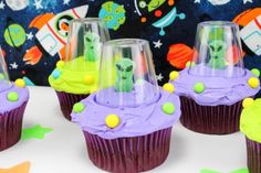 three alien cupcakes with purple frosting and green sprinkles on them