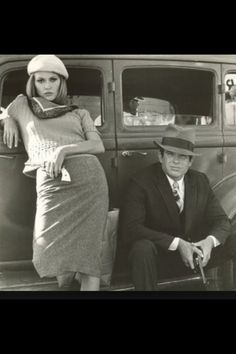 an old black and white photo of two people in front of a car