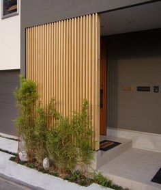 an entrance to a building with wooden slats on the side and plants in front