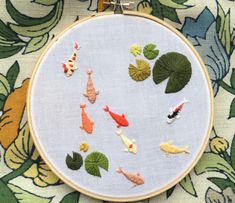 a close up of a cross stitch pattern with fish and waterlilies on it