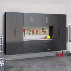 a garage with cabinets and tools on the floor, in front of a white wall