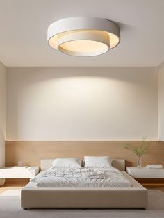 a large white bed sitting in a bedroom next to a wall mounted ceiling light fixture