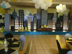 tables and chairs are set up for a party with balloons in the shape of cityscapes