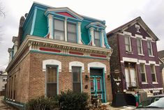 two houses with blue and red trim on the roof, one has a car parked in front of it