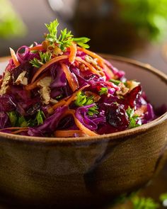 a wooden bowl filled with red cabbage and carrots