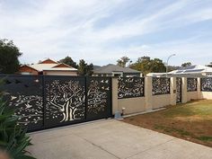 a fence that has trees on it and birds in the tree, is next to a house