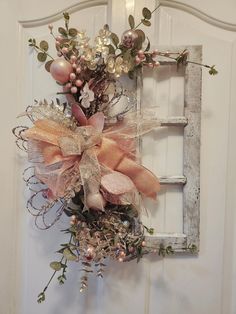 an old window frame is decorated with pink and gold flowers, greenery, and bows