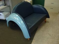 a blue couch sitting in the middle of a room next to some shelves and drawers