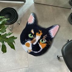 a cat rug is on the floor next to a plant