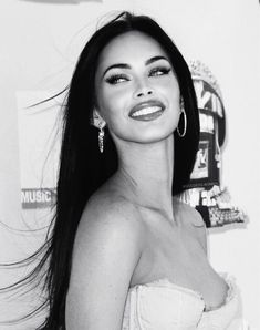 a black and white photo of a woman with long dark hair smiling at the camera