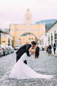 a bride and groom kissing on the cobblestone street