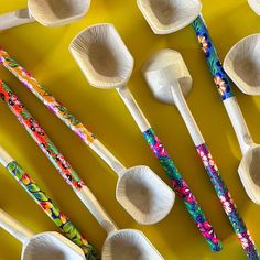 many spoons are lined up on a yellow surface with different designs and colors in them