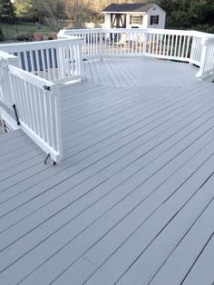 a deck with white railings and two benches on the bottom level, overlooking a house