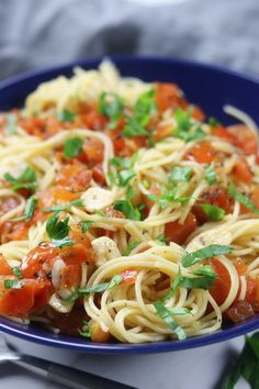 a blue bowl filled with pasta and vegetables