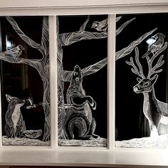 three glass panels depicting animals and birds in the woods at night, with one deer looking out