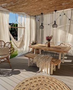 an outdoor area with hammock chairs, table and rugs on the floor