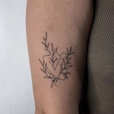 a woman's arm with a heart and leaves tattoo on the left side of her arm