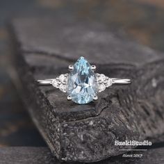 a blue topazte and diamond ring sitting on a rock