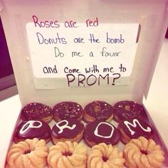 a box filled with lots of donuts next to a sign that says roses are red donuts are the bomb do me a four and come with me to prom