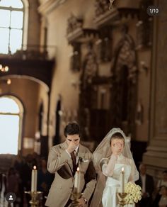 a bride and groom standing in front of candles