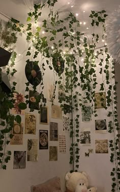 a teddy bear sitting on a couch in front of a wall covered with plants and pictures