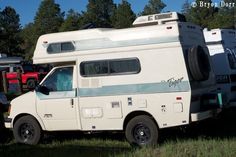 an rv is parked in the grass near other vehicles