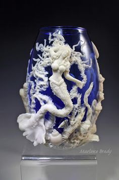 a blue and white vase sitting on top of a glass stand with seahorses