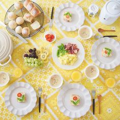 a yellow table cloth with white plates and silverware on it