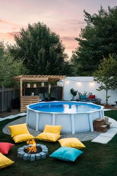 an above ground pool surrounded by pillows and fire pit in the middle of a backyard