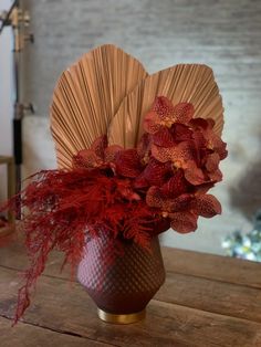 a vase filled with red flowers on top of a wooden table