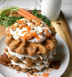 a stack of waffles topped with whipped cream, carrots and pecans