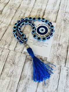 the evil eye beaded bracelet with blue tassels is laying on top of a card