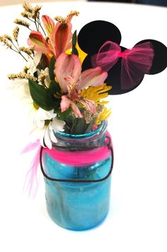 a blue mason jar filled with flowers and minnie mouse ears