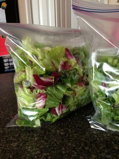 two bags filled with lettuce and radishes sitting on top of a counter