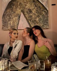 three women sitting at a table with drinks