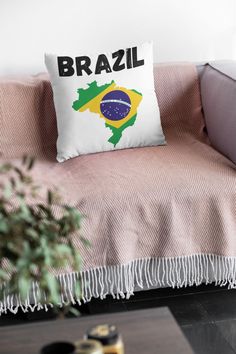 a couch with a pillow that has the brazilian flag on it and is next to a potted plant