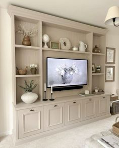 a large flat screen tv sitting on top of a wooden shelf in a living room