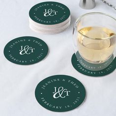 three coasters with the names and date on them next to a glass of wine