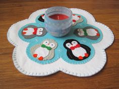 a table with a cup on it next to a candle holder and coasters that have penguins on them