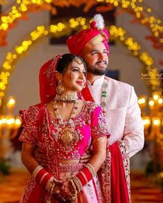 a bride and groom posing for a wedding photo in front of an archway decorated with lights