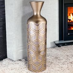 a gold vase sitting on the floor next to a fire place in a living room